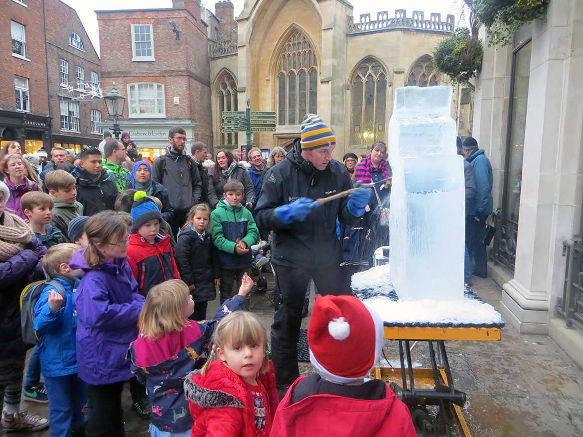A crowd is enthralled by the artist at work