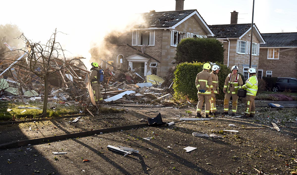 Firefighters survey the remains of the house. Photograph: Nigel Holland