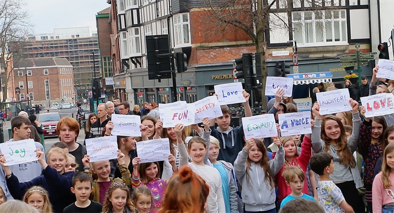 The students hold up their own signs at the end of the flashmob