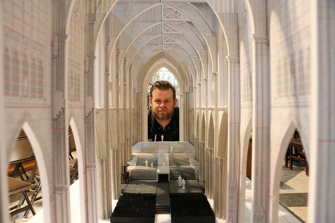 Designer Max Jones looks through the nave of his model set 
