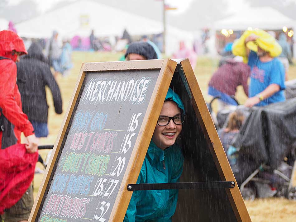A Young festival goer hides from the rain