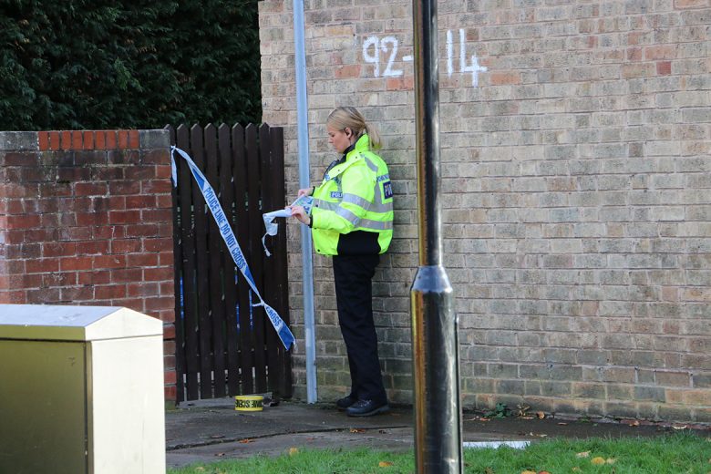 A police officer tapes up a gate giving access to the rear of the property