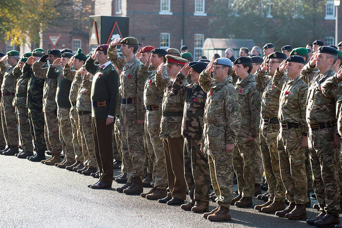 The senior officers from 1 (UK) Division at the front saluting during the Last Post
