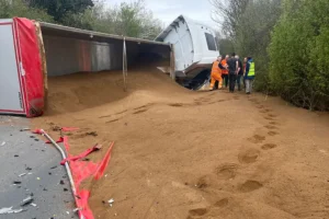 Road closed after lorry crash spills sand over the highway
